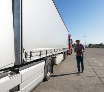 Truck driver inspecting vehicle trailer tires before driving min 360x320